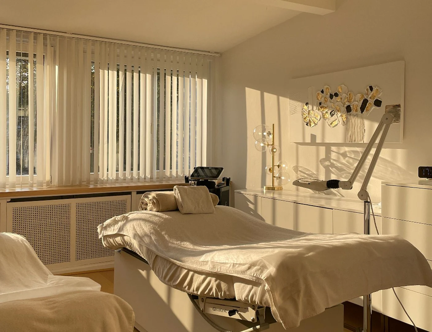 Behandlungszimmer mit gepolsterter Liege, großen Fenstern und Behandlungsgeräten